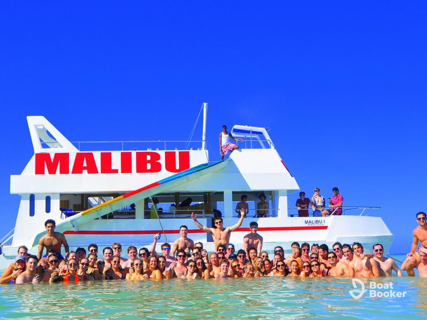 A vibrant group of friends enjoys a fun day in the water around the Malibu boat, celebrating with drinks and laughter — perfect for party cruises and group outings.
