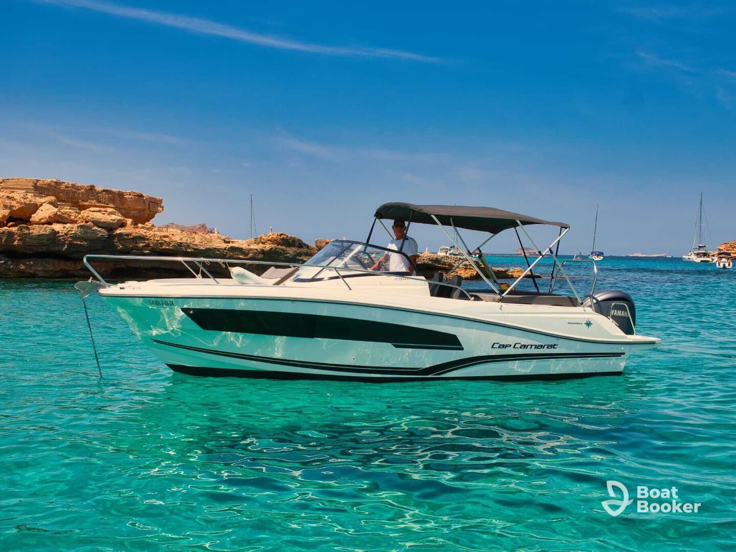 A sleek Cap Camarat speedboat glides through crystal-clear waters, showcasing its elegant design against a stunning coastal backdrop.