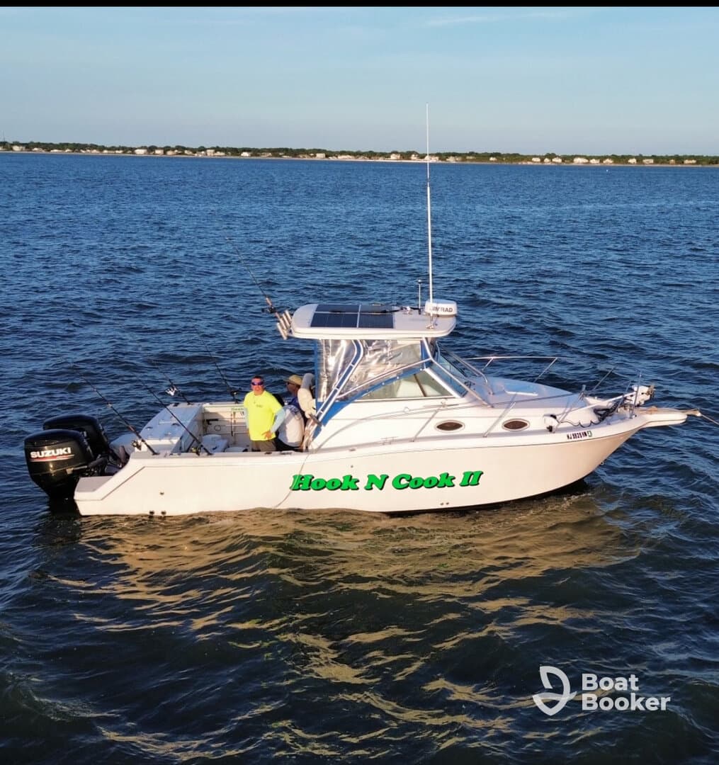 Two fishermen aboard the 'Hook N Cook II' enjoy a day out on the water, showcasing the perfect setting for a fishing adventure.