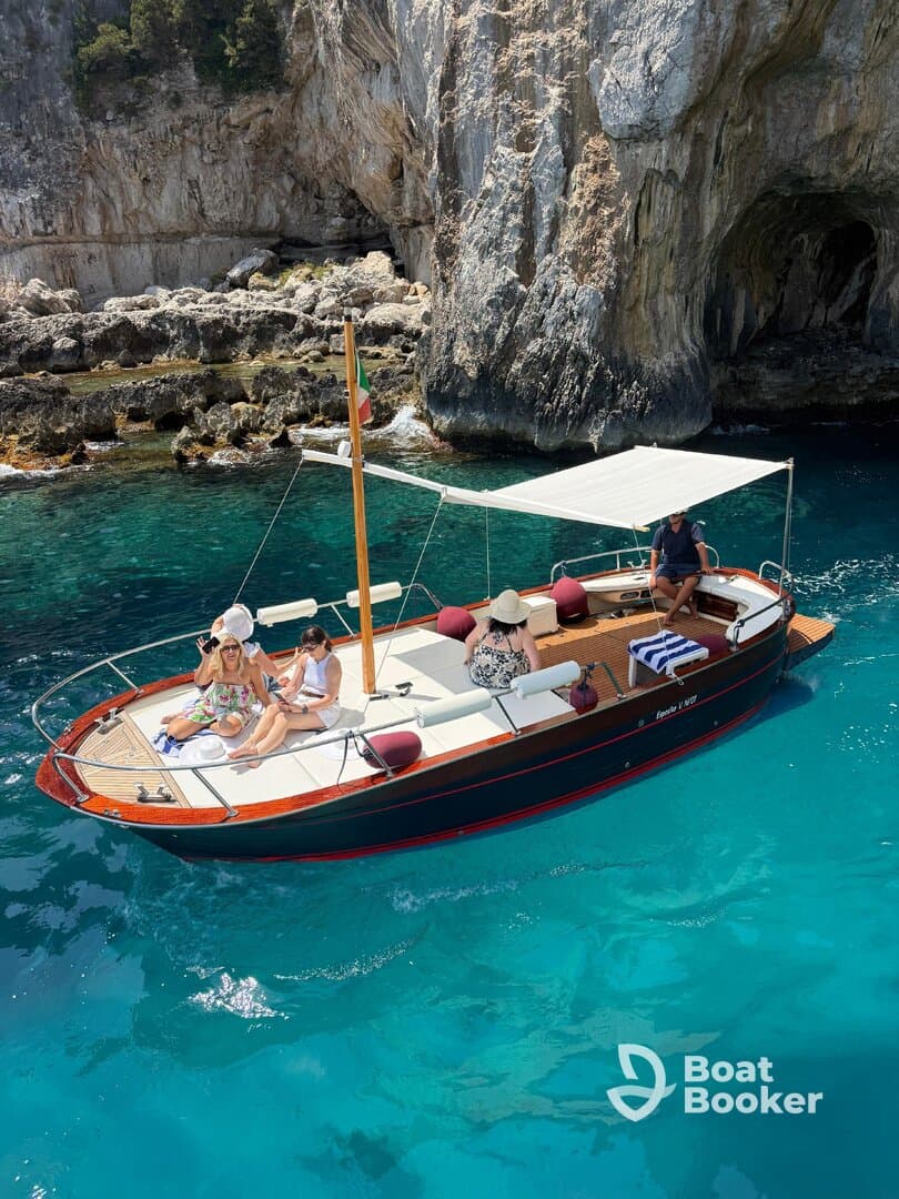 A lively group enjoys a sun-soaked day on a boat, surrounded by stunning turquoise waters and rocky cliffs — perfect for summer adventures and celebrations.