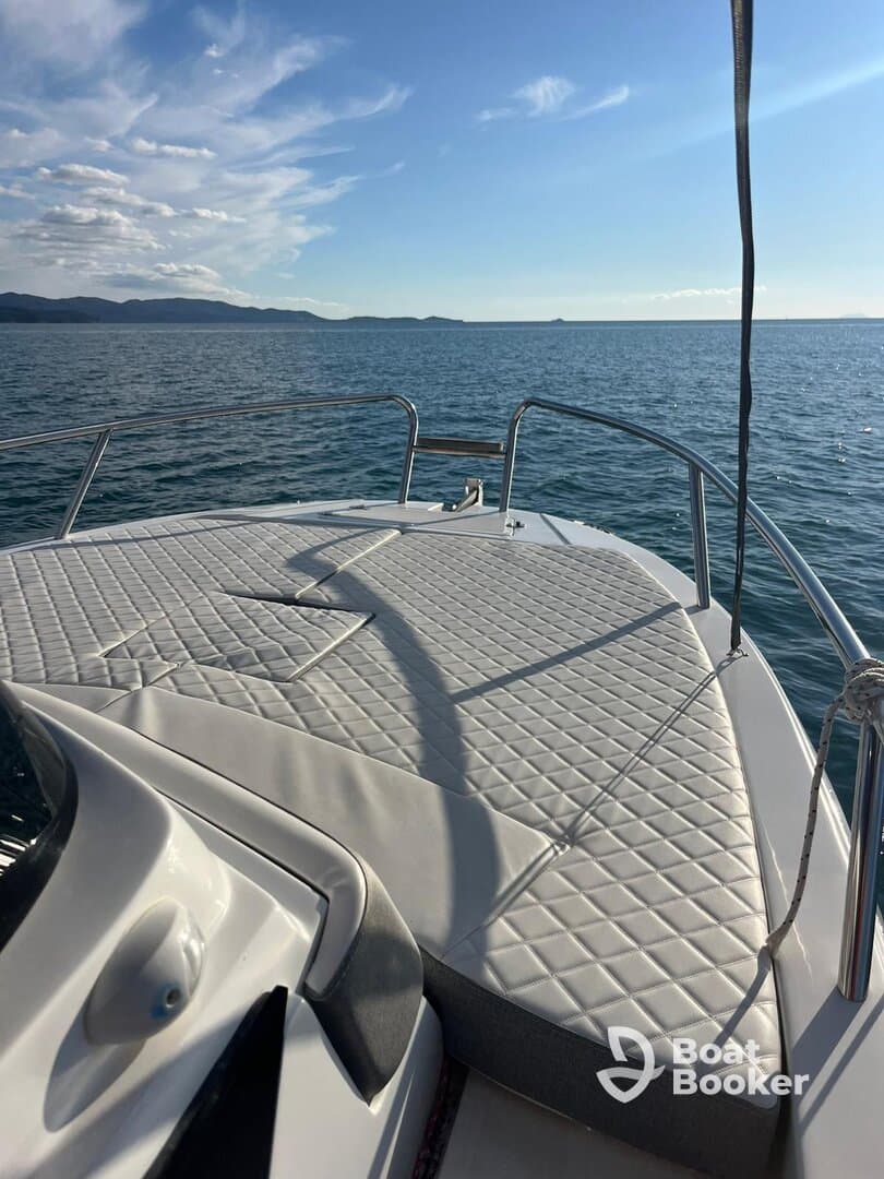 A serene view of the front deck of a boat, showcasing its sleek design against a backdrop of calm waters and distant mountains — perfect for leisurely outings on the water.