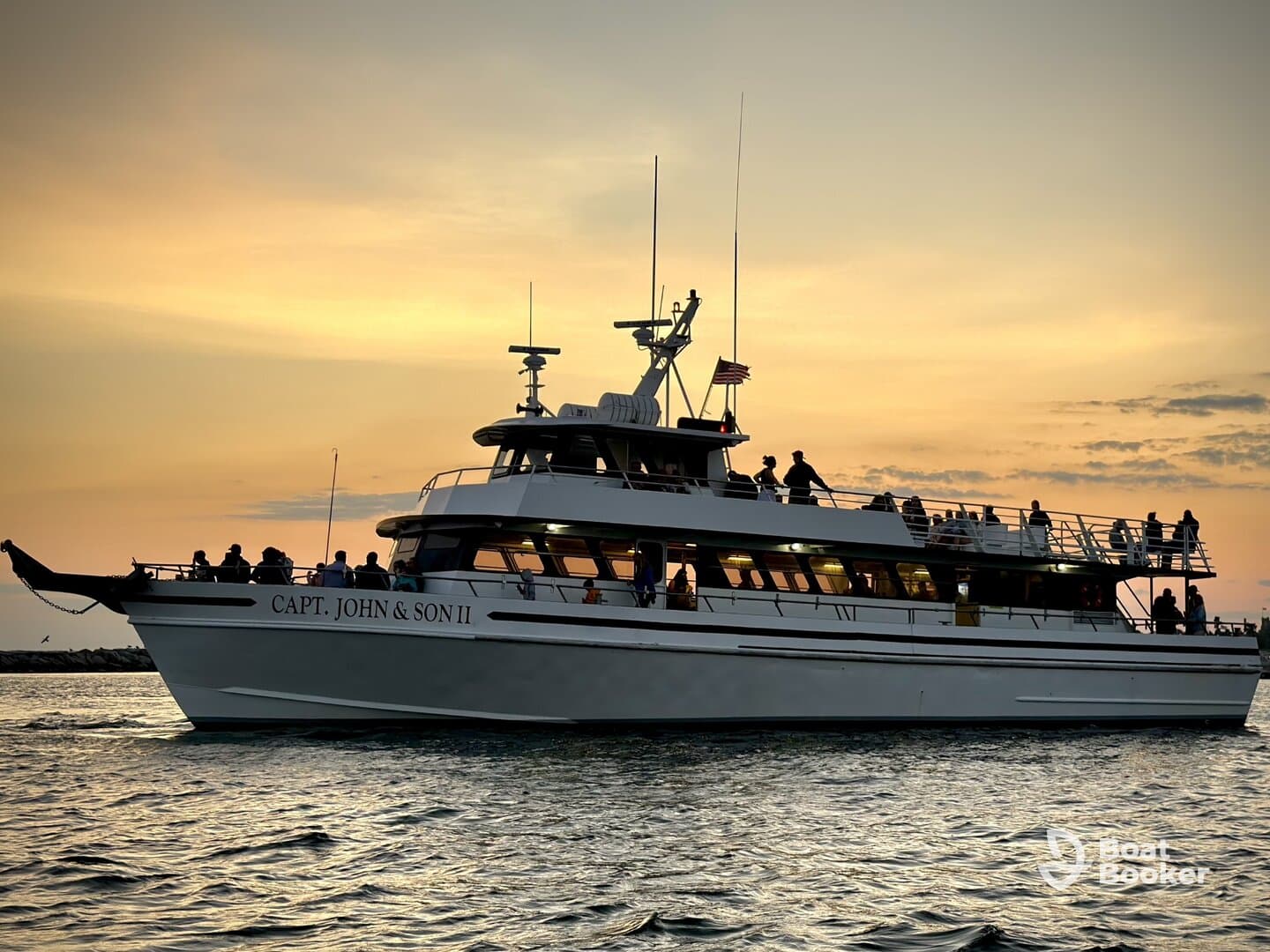 The 'Capt. John & Son II' yacht glides through the water at sunset, with guests enjoying the scenic views — a perfect setting for evening cruises and celebrations.