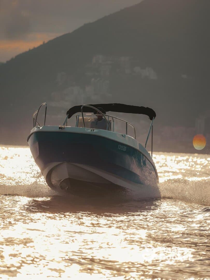 A sleek speedboat navigates through shimmering waters, showcasing its dynamic design against a stunning sunset backdrop.