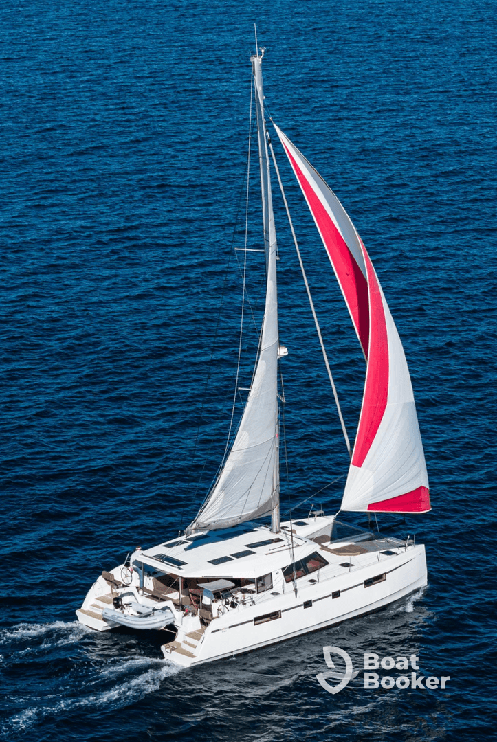 A stunning aerial view of a sleek catamaran sailing through deep blue waters, showcasing its elegant design and spacious deck — perfect for luxury charters and sailing adventures.