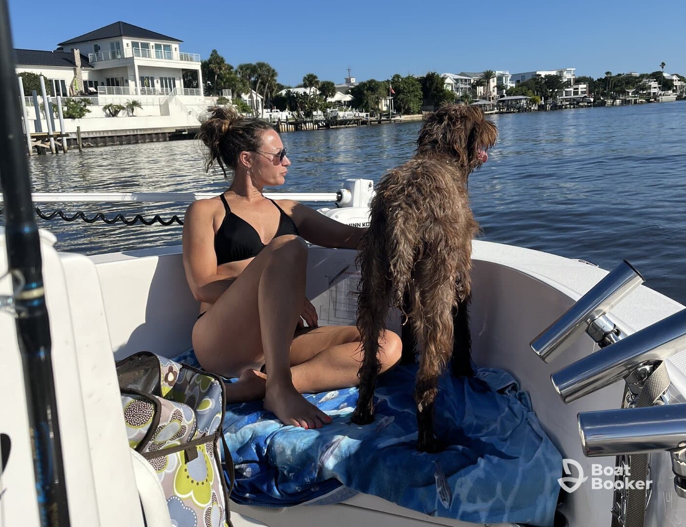 A woman enjoys a sunny day on the boat with her dog, taking in the scenic waterfront views — a perfect moment for relaxation and companionship on the water.