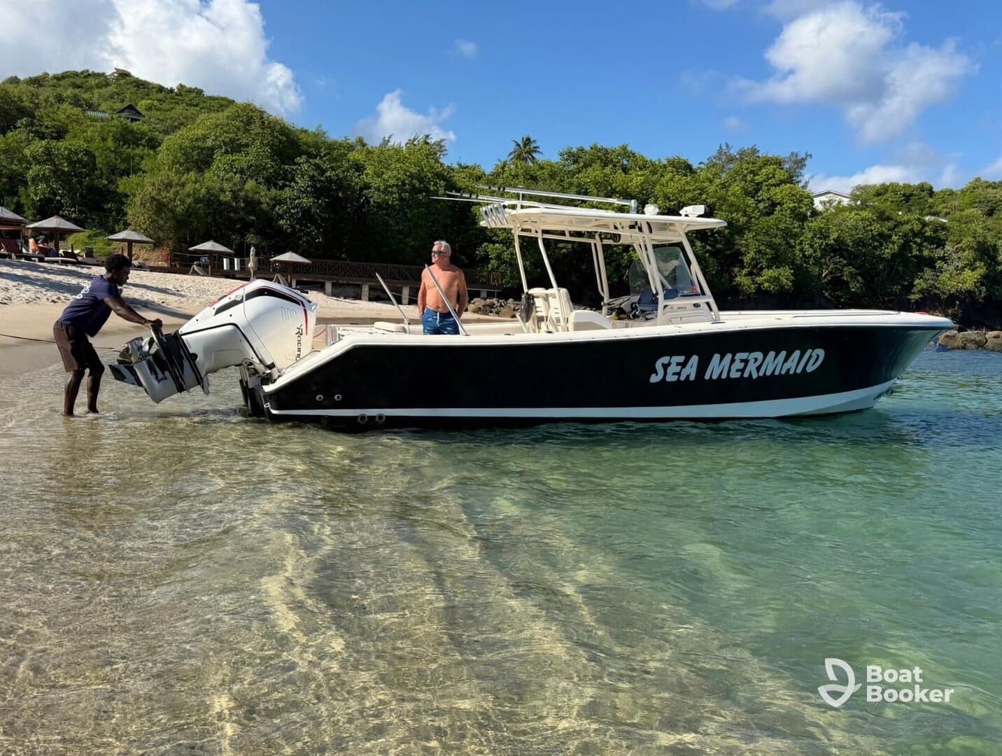 A crew member assists with the outboard motor on the 'Sea Mermaid' boat as it approaches the beach, showcasing a lively day on the water.