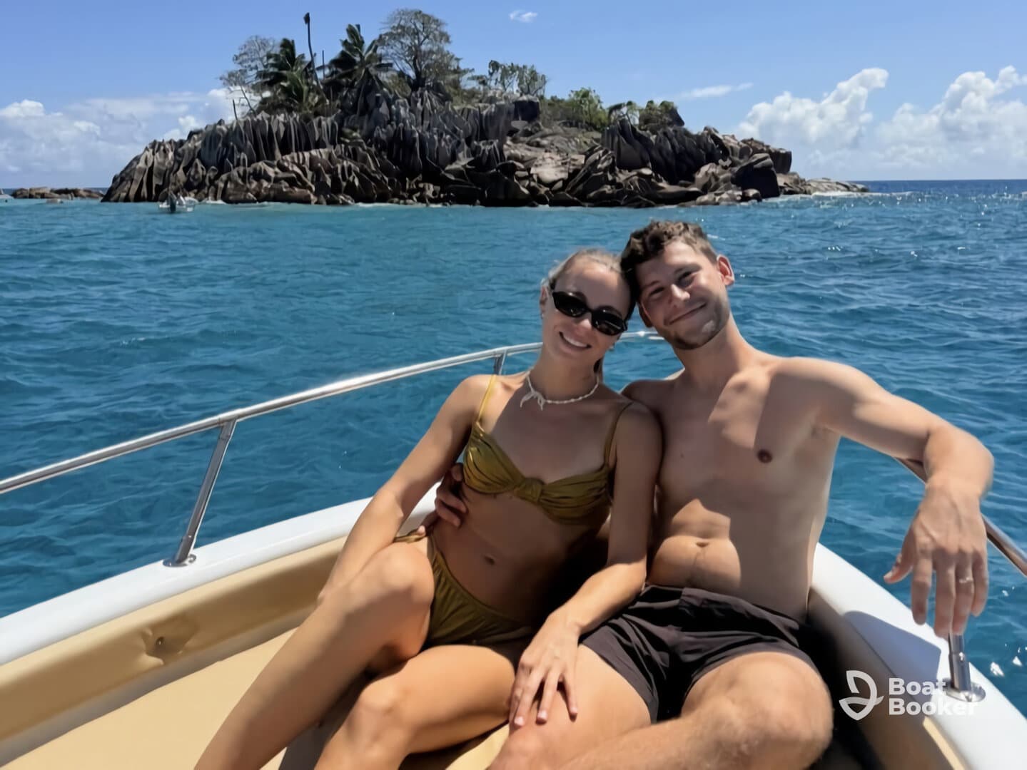 A couple enjoys a sunny day on a boat, smiling and relaxing with a picturesque island backdrop — perfect for romantic getaways or fun adventures on the water.