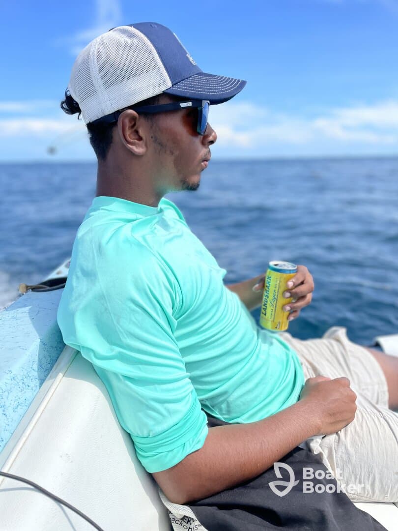A young man enjoys a refreshing drink while relaxing on a boat, capturing the essence of a laid-back day on the ocean.