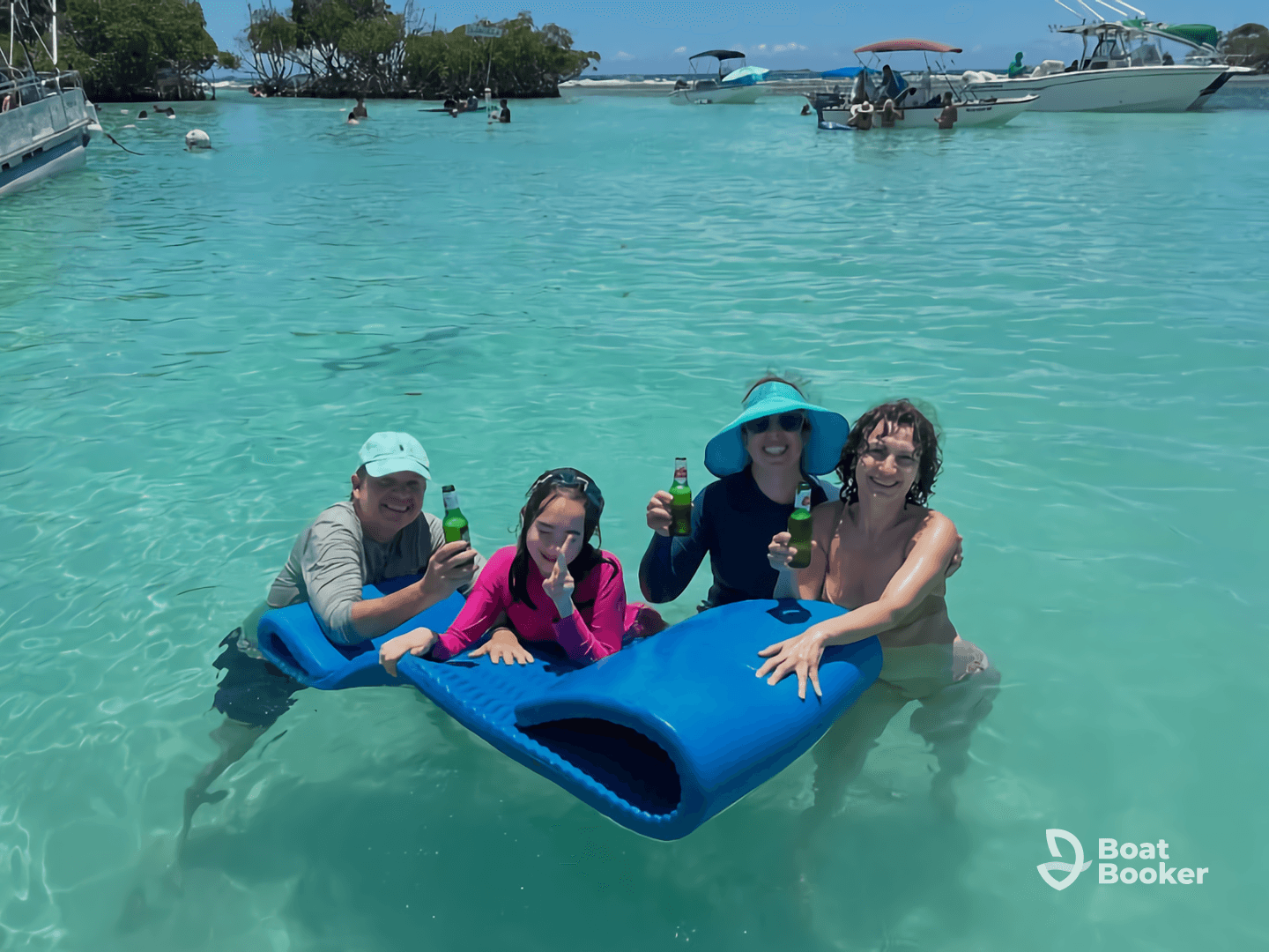 A joyful group enjoys a sandbar stop, relaxing in the clear waters with drinks in hand — a perfect day for fun and laughter under the sun.