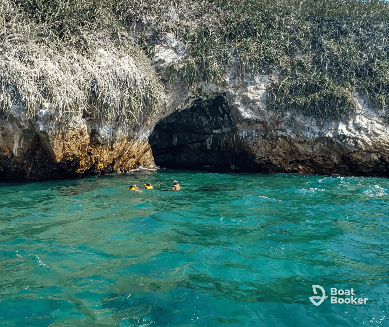 A group of snorkelers explores a stunning cave entrance in crystal-clear waters, showcasing the beauty of underwater adventures.