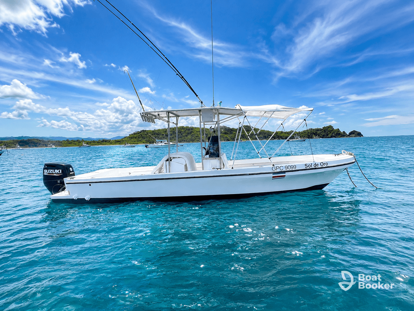 A sleek speedboat named 'Sol de Oro' glides through crystal-clear waters, showcasing its elegant design against a picturesque backdrop of lush greenery and blue skies.