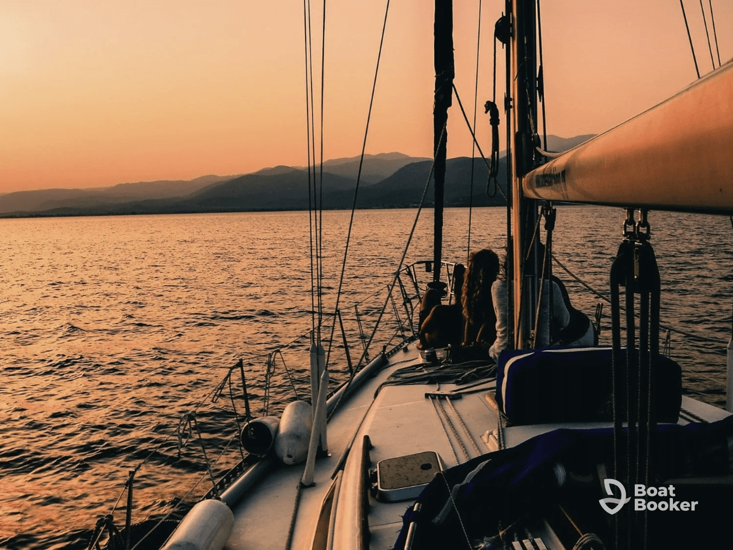 A serene sunset view from a sailboat with friends enjoying the tranquil waters, perfect for a memorable sailing experience.