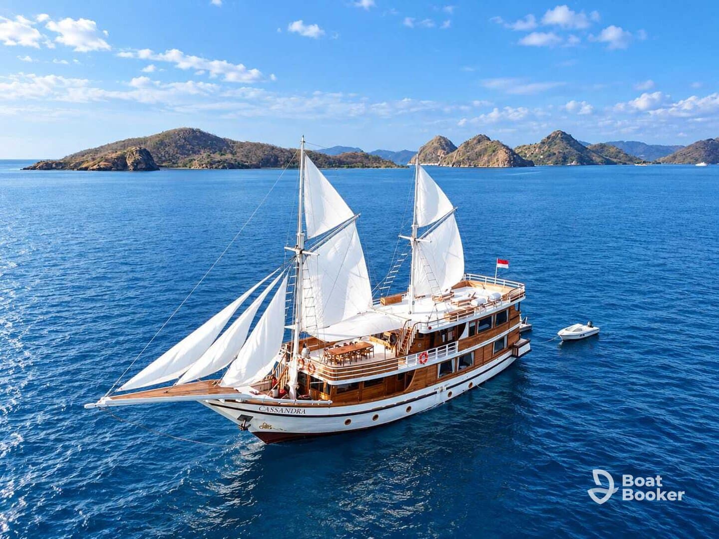 A stunning aerial view of the sailing yacht 'Cassandra' gliding through crystal-clear waters, surrounded by picturesque islands — perfect for luxury charters and scenic voyages.
