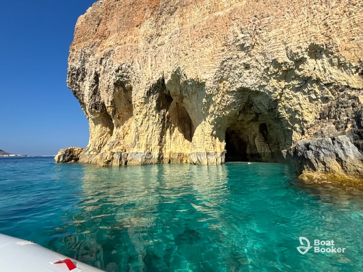 A stunning view of a rocky coastline and cave, surrounded by crystal-clear turquoise waters — a perfect destination for exploring natural beauty by boat.