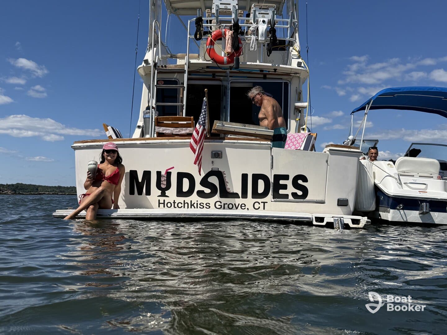 A lively scene on the boat 'MUDSLIDES' with guests enjoying drinks and relaxing in the water — perfect for summer fun and social gatherings.