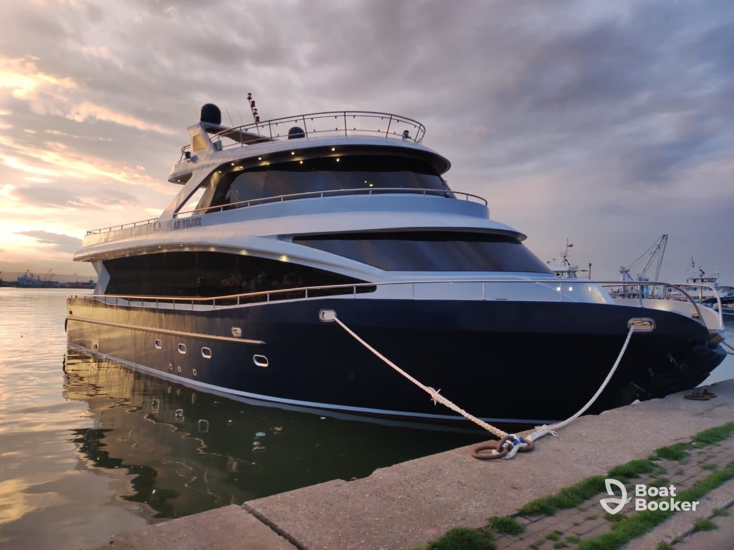 A stunning yacht docked at the harbor, showcasing its elegant design against a picturesque sunset backdrop.
