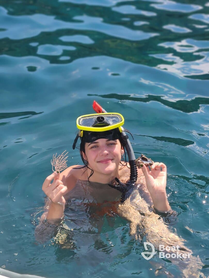 A young snorkeler holds a sea creature while enjoying the vibrant underwater world, showcasing a unique human-animal interaction in crystal-clear waters.