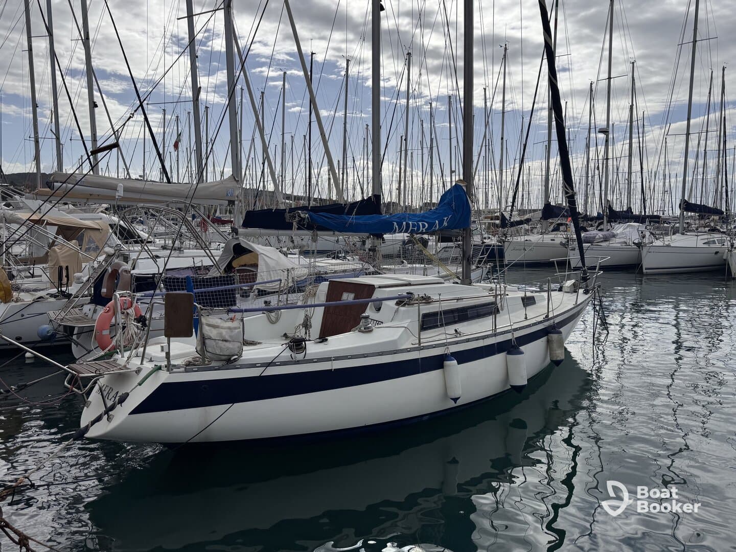 A beautiful yacht docked in a marina, surrounded by other boats and masts, showcasing the serene atmosphere of a sailing destination.