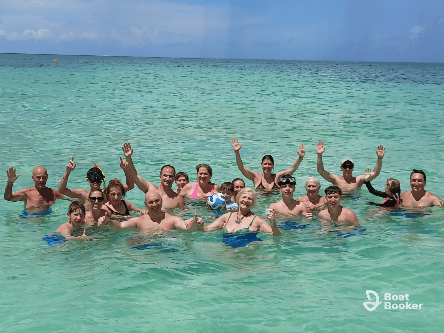 A lively group enjoys a fun day swimming in crystal-clear waters, showcasing a perfect blend of family and friends celebrating together.