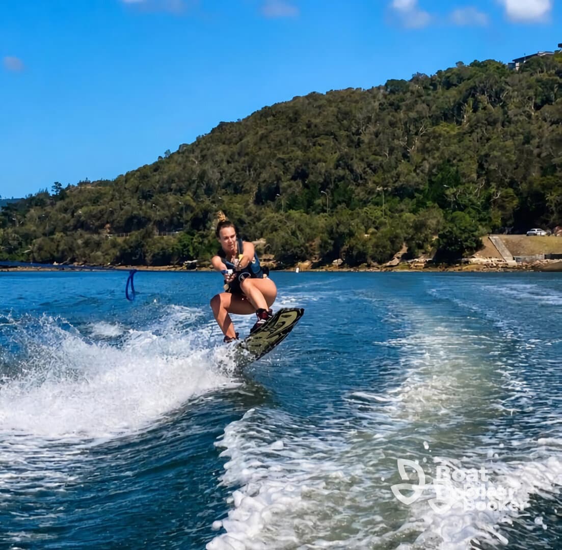 A thrilling moment captured as a wakeboarder performs an impressive jump over the waves, showcasing the excitement of water sports in a scenic setting.