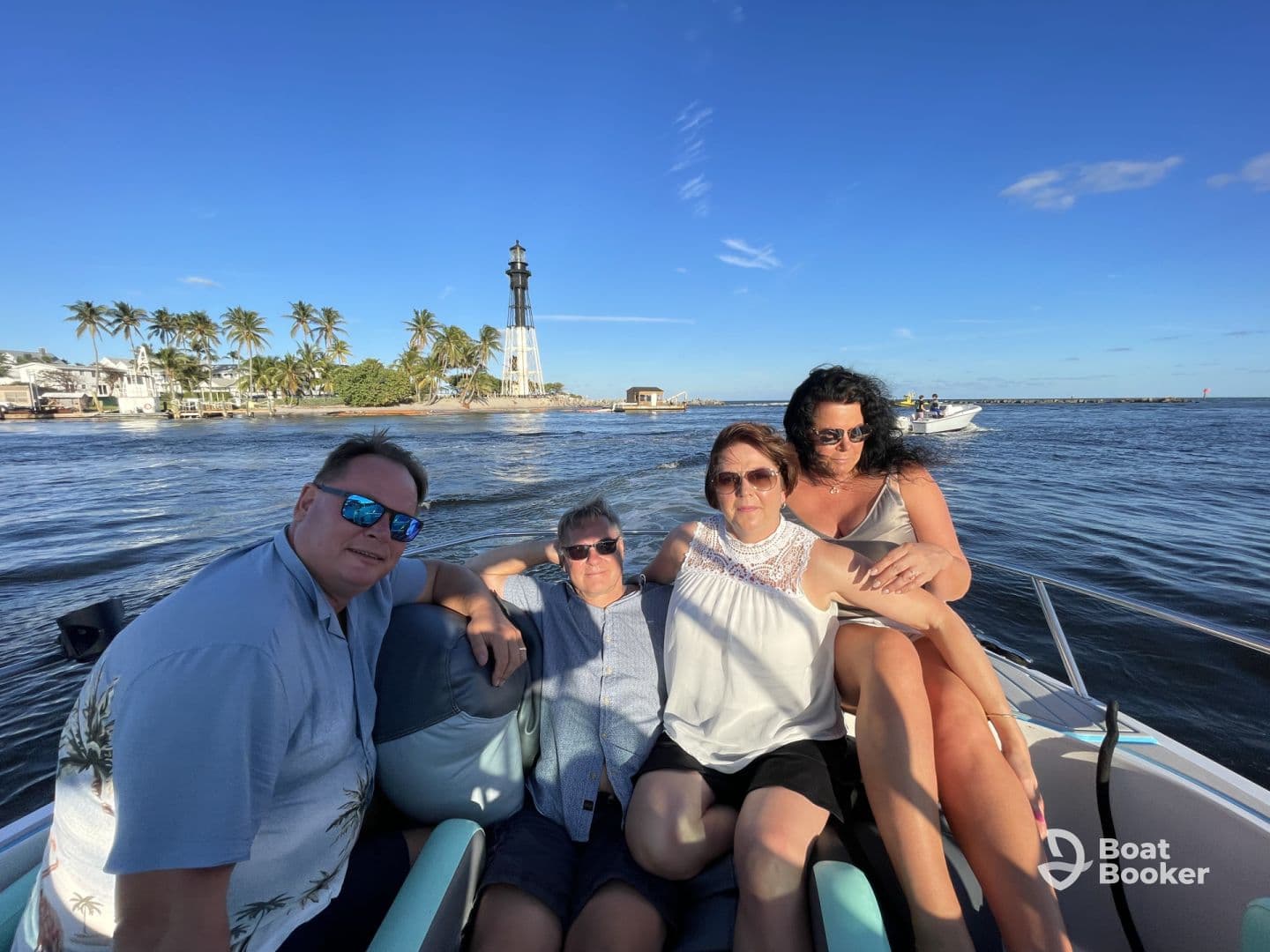 A cheerful group enjoys a boat ride with a scenic lighthouse in the background, perfect for memorable outings and celebrations on the water.