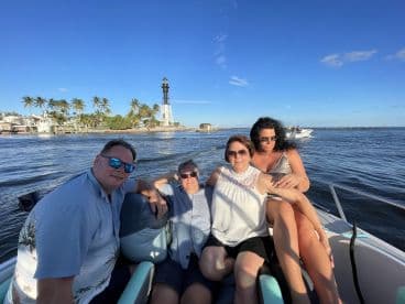 A cheerful group enjoys a boat ride with a scenic lighthouse in the background, perfect for memorable outings and celebrations on the water.