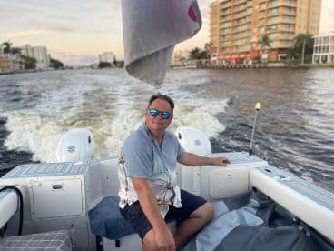 A man enjoys a leisurely cruise on a boat, showcasing the vibrant waterfront scenery — perfect for a relaxing day on the water.