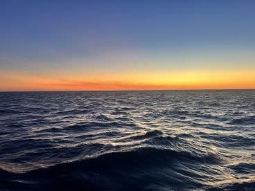 A serene view of the ocean at sunset, capturing the beautiful gradient of colors in the sky. Ideal for tranquil moments on the water.