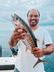 A joyful angler proudly displays his catch while fishing in the ocean, showcasing the thrill of a successful day on the water.
