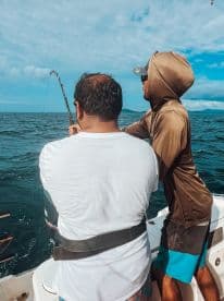 Two anglers enjoy a fishing trip on the open water, showcasing the thrill of reeling in a catch while surrounded by beautiful ocean scenery.