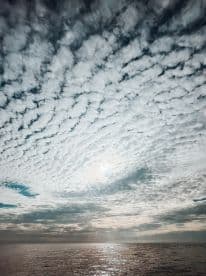A scenic view of a cloudy sky reflecting over the ocean, creating a tranquil atmosphere.