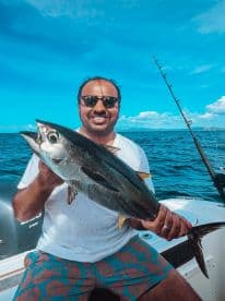 An enthusiastic angler proudly displays his catch while fishing in the ocean, showcasing the thrill of a successful day on the water.