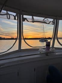 A serene view from inside the cabin of a boat, showcasing a beautiful sunset over the water, perfect for relaxing moments on the water.