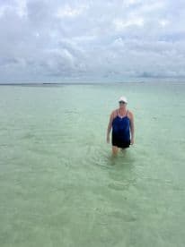 A woman wades through shallow, clear waters, enjoying a serene beach experience — perfect for relaxation and exploration in tropical destinations.