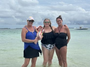 A joyful group of women and a baby enjoy a day at the beach, creating cherished memories in the water — perfect for family outings and beach adventures.