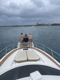 A group of friends enjoys the view from the bow of a yacht, creating memorable moments on the water amidst a scenic backdrop.