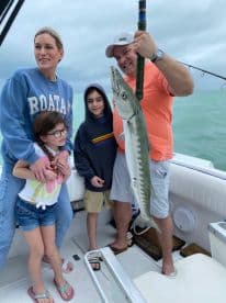 A family proudly displays their catch while fishing on a boat, capturing a memorable moment of togetherness and adventure on the water.