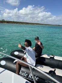 A couple enjoys a thrilling whale ride on a sunny day, showcasing the vibrant turquoise waters and a fun boating experience.