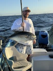 A proud angler holds up his impressive catch while fishing on the open ocean, showcasing the thrill of a successful day on the water.