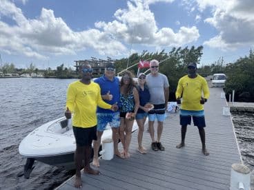 A cheerful group poses on the dock next to their boat, celebrating a day on the water — perfect for memorable outings and adventures.