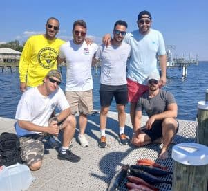 A group of friends proudly poses on the dock with their catch of the day after a successful fishing trip, showcasing camaraderie and outdoor adventure.
