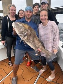 A joyful group celebrates their fishing success, showcasing a large catch aboard a boat — perfect for family fishing trips and memorable moments on the water.