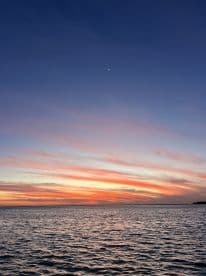 A serene sunset over the water, showcasing vibrant colors in the sky. Ideal for capturing the beauty of nature.