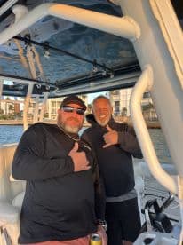 Two friends share a moment aboard a boat, showcasing camaraderie and fun on the water — perfect for memorable outings with friends.