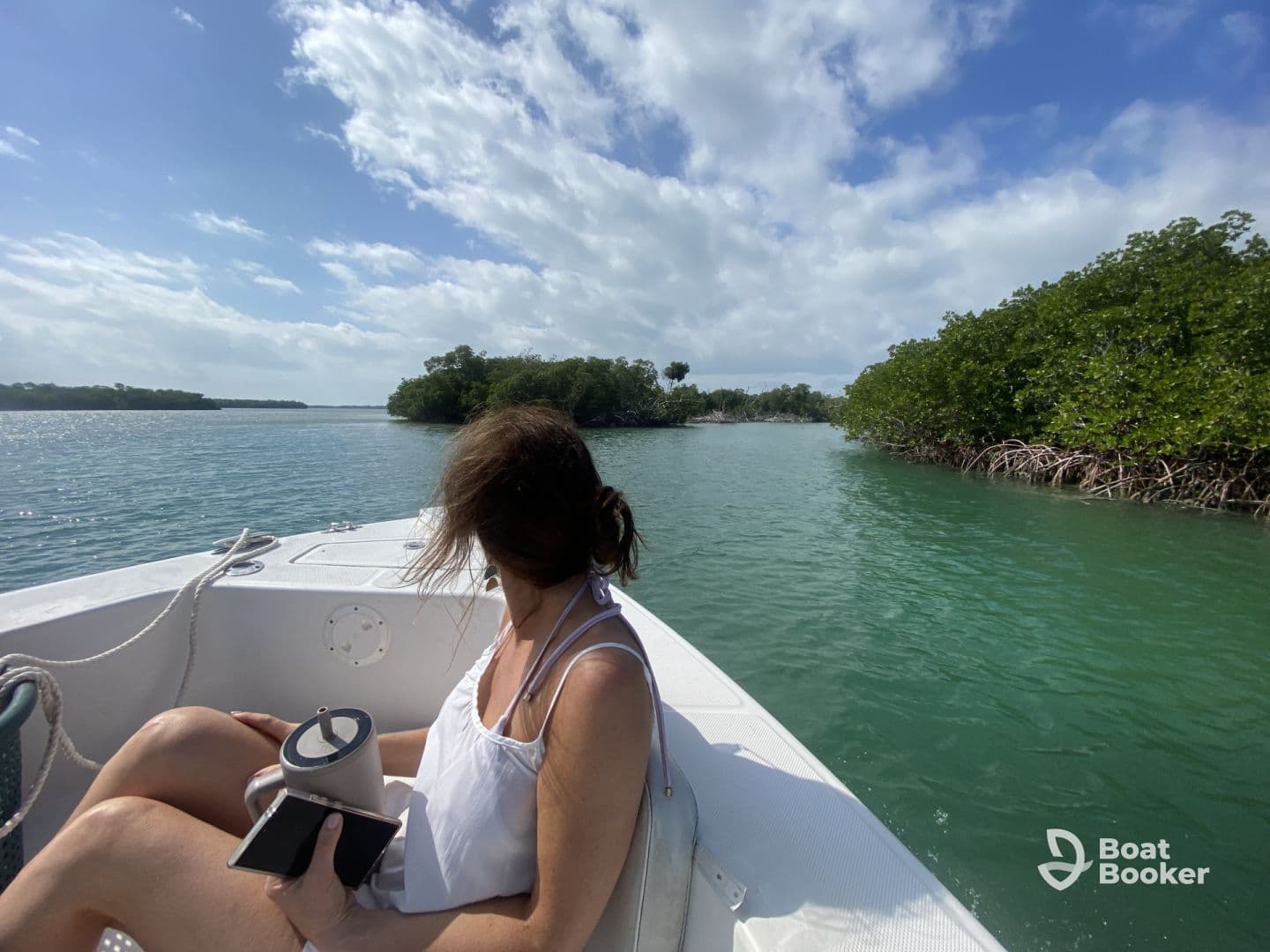 A woman enjoys the scenic view of mangroves while relaxing on a boat, capturing the essence of a tranquil day on the water.