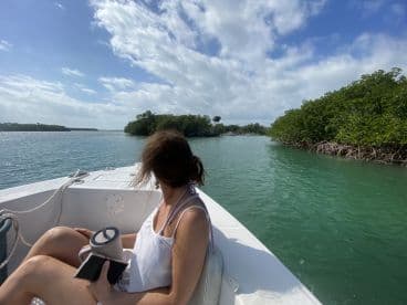 A woman enjoys the scenic view of mangroves while relaxing on a boat, capturing the essence of a tranquil day on the water.