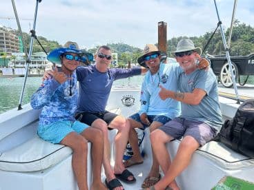 A cheerful group of friends enjoys a fishing trip on a boat, showcasing camaraderie and adventure on the water.