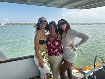 Three friends pose together on the deck of a boat, enjoying a sunny day on the water — perfect for memorable outings and celebrations.