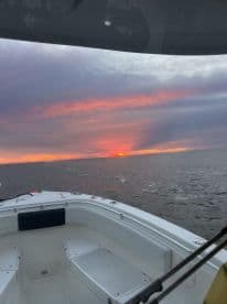 A serene sunset view from the deck of a boat, showcasing the tranquil waters and vibrant sky — perfect for evening cruises.