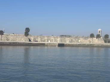 A scenic view of a historic landmark along the coastline, with visitors enjoying the sights from the water — perfect for sightseeing tours.